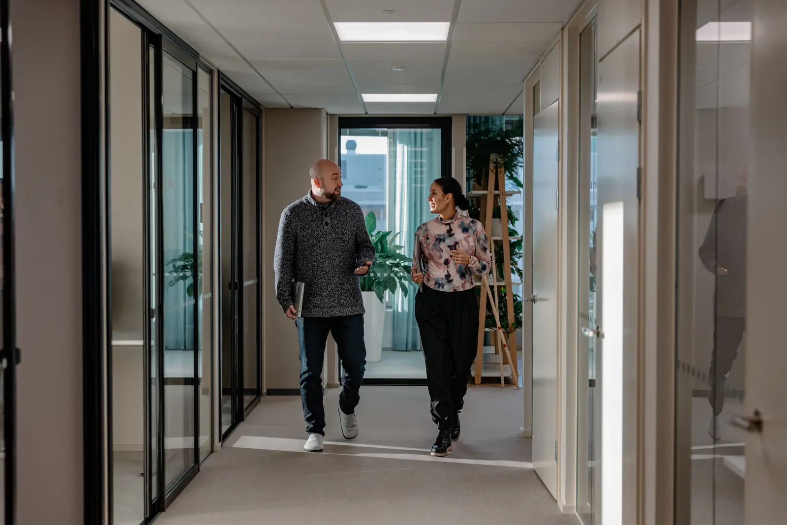 Two M-Files colleagues walking and talking in the office hallway